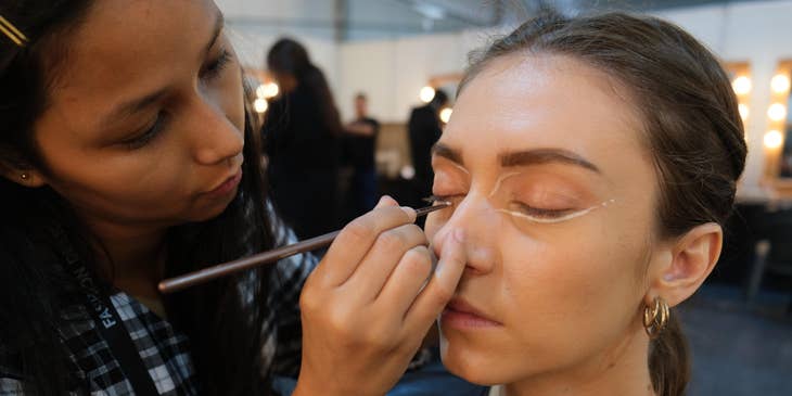 A special effects makeup artist applying makeup to an actor.