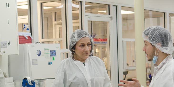 A specimen processor speaking with a coworker in a laboratory.