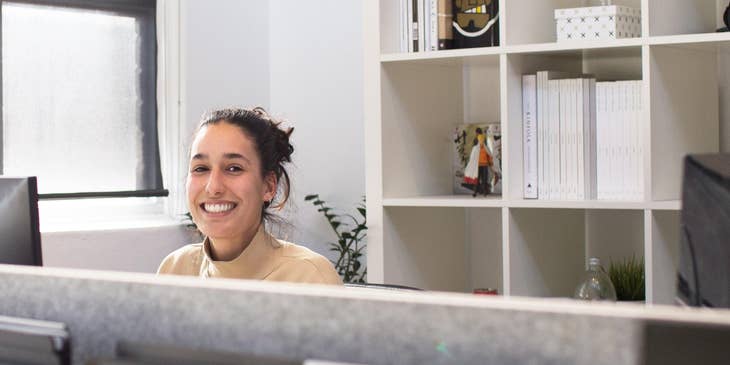 A unit clerk sitting behind a medical reception desk.