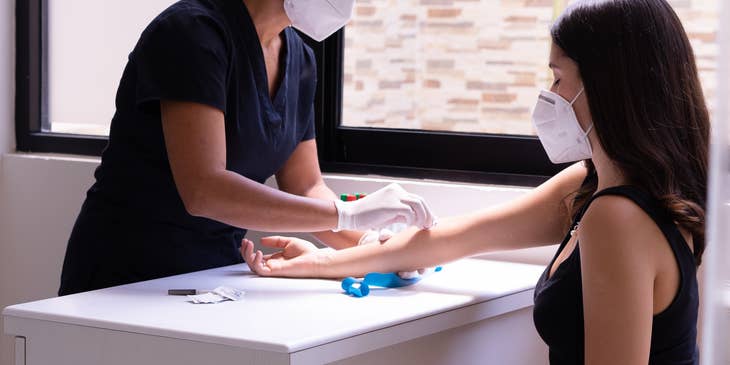 A medical assistant wiping the arm of a patient.