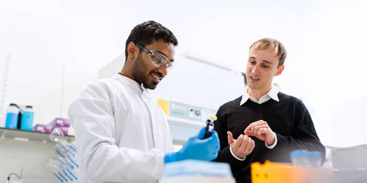 Biochemical Engineer conducting research in a laboratory and showing a vial to his assistant