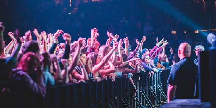 Bouncers stationed in front of the stage facing the crowd during an ongoing performance