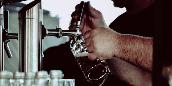 A Brewmaster pouring crafted beer into a glass for taste testing to ensure beer is in perfect quality.