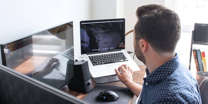 C++ Developer optimizing the software program on his laptop together with a desktop computer