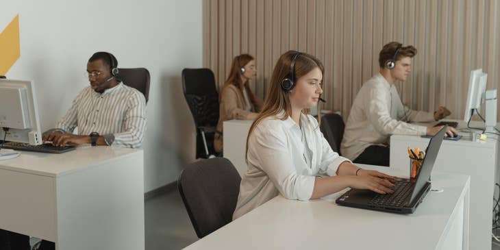 Call Center Representatives working on their designated workstations while wearing headsets and looking at their computers