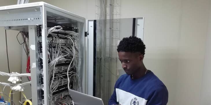 Certified Ethical Hacker holding his laptop while connected to the server and doing penetration tests to the system