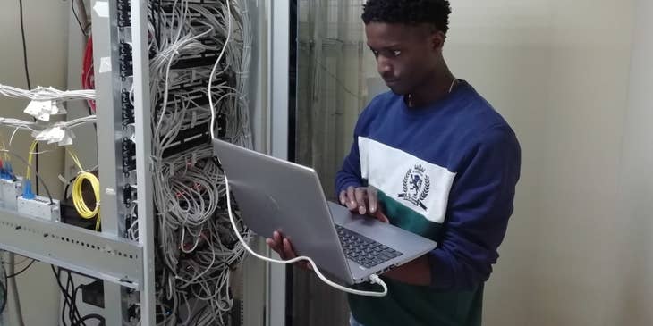 Certified Ethical Hacker holding his laptop while connected to the server and doing penetration tests to the system