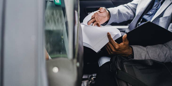 A Claims Adjuster inside a vehicle examining reports filed by claimant regarding a damaged vehicle.