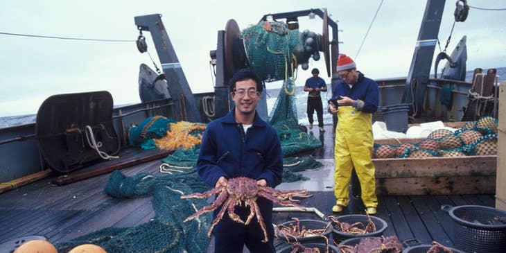 Commercial Fisherman showing off a king crab on deck after sorting the day's catch