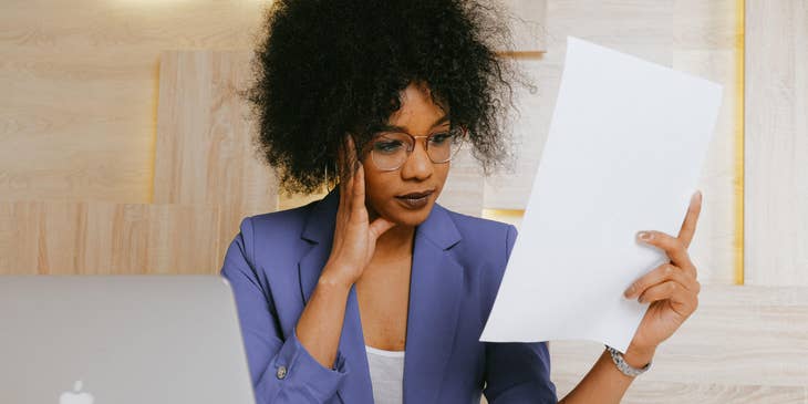 A commodity manager working on her laptop looking at a piece of paper.