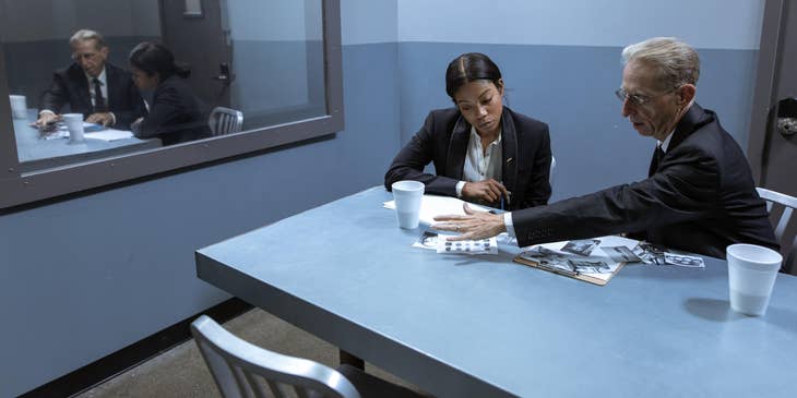 A Female Criminal Profiler working together with an investigator examining photos of evidences collected at a crime scene.