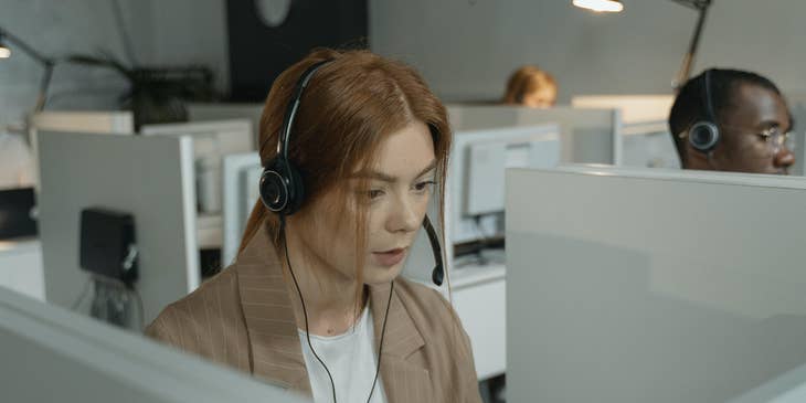 female Customer Support Representative wearing her headset while looking at the computer on her workstation