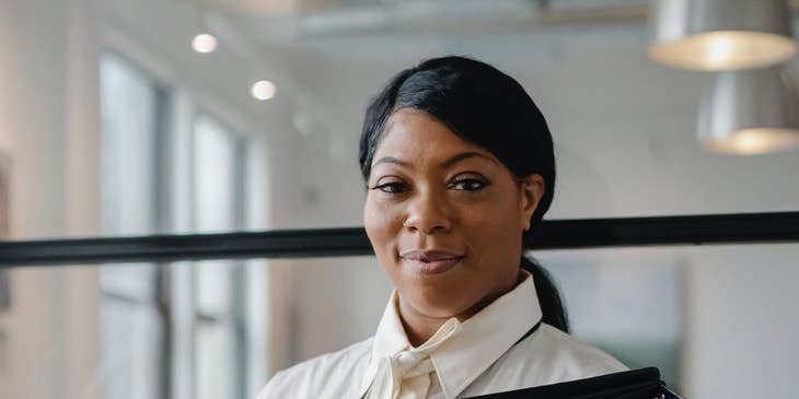 A data entry specialist in a white shirt holding a stack of black files.