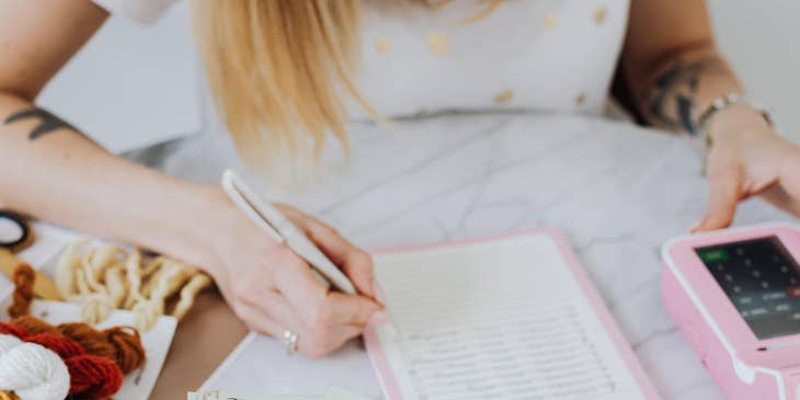 A Female Dental Insurance Coordinator processing a payment and writing notes on a notebook.