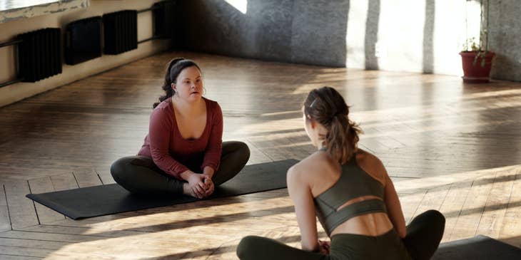 Direct Support Professional sitting on the floor doing yoga with her client