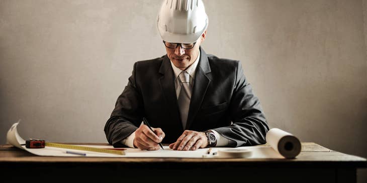 Director of Engineering wearing a hard hat and business suit while reviewing the blueprint of one of the company's physical assets