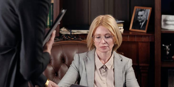 A Female District Attorney Investigator working with a District Attorney and presenting documents for a case.