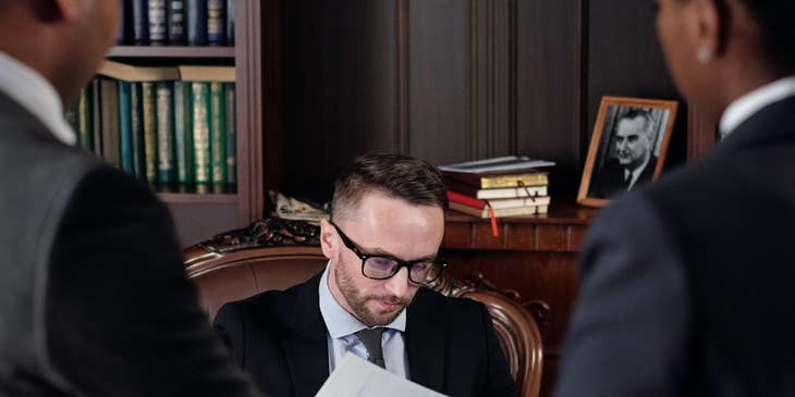 A District Attorney reviewing and analyzing  some legal case documents presented to him by his associates.