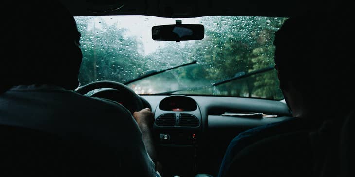 Driving instructor teaches a new driver how to control the car safely when raining