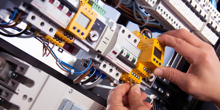 Electrical technician fixing cable wires in a panel board