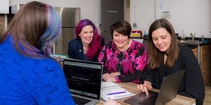 female Engagement Manager presenting details from her laptop to the client's team inside the office room