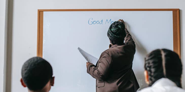 English Teacher starts the class by writing something on the board for the students to read