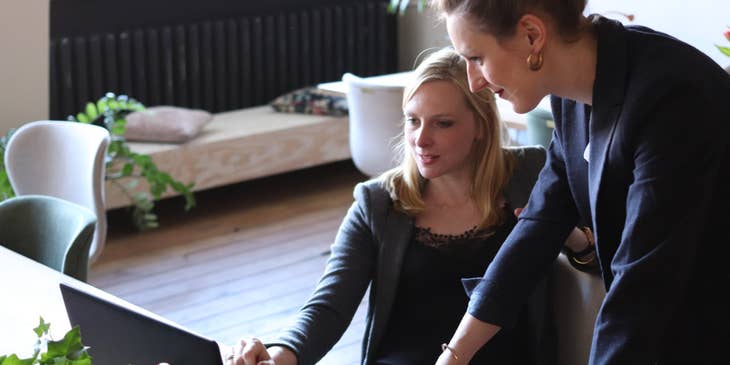 ERP Specialist showing the result of her client's system integration to the product to her colleague standing beside her