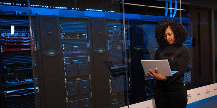 ETL Developer performing tests on the storage systems on her laptop while standing outside the server room