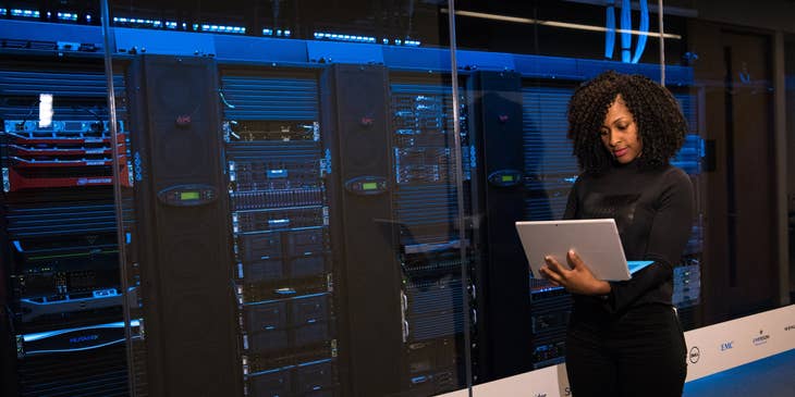 ETL Developer performing tests on the storage systems on her laptop while standing outside the server room