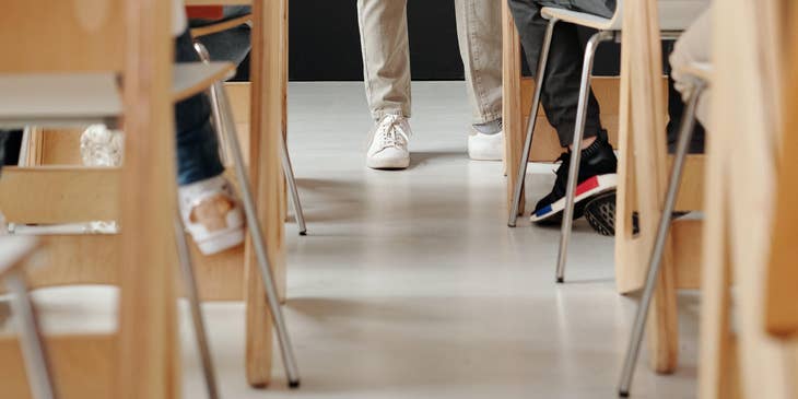 Examiner stands in the middle of the classroom while students are taking the exam