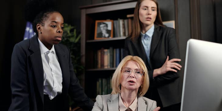 A Female Family Lawyer sitting in fron of her computer coordinating and discussing a case with her staff.