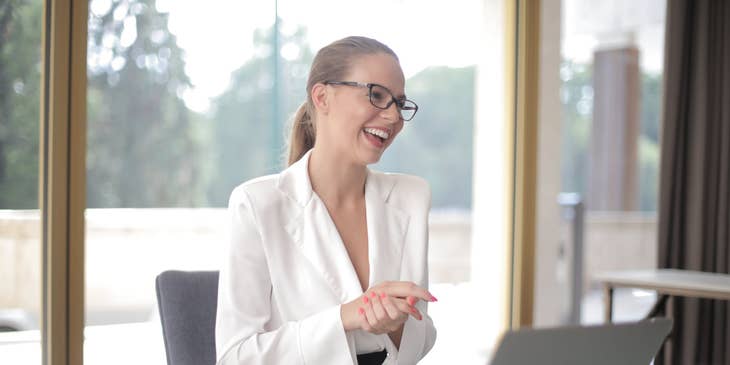 female Finance Assistant wearing eyeglasses and sitting in front of a table with an open laptop