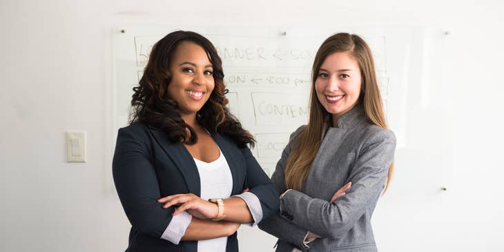 Finance Manager with her female colleague standing cross-armed in front of a white board