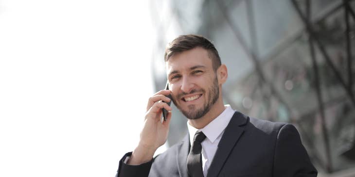 Financial Officer wearing a black business suit while holding a mobile phone