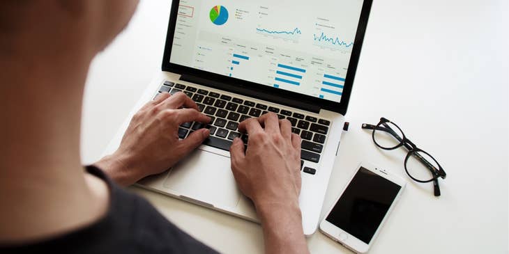 Financial Planner generating a graph report on his laptop with his eyeglasses and mobile phone on the table