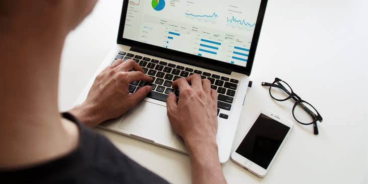 Financial Planner generating a graph report on his laptop with his eyeglasses and mobile phone on the table