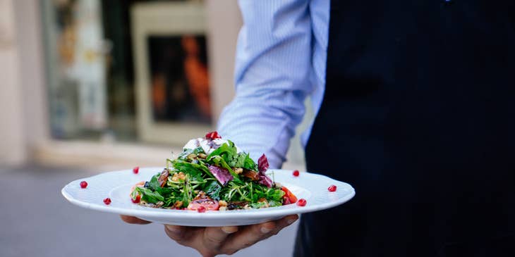 Food Service Worker serving a salad to the customer.