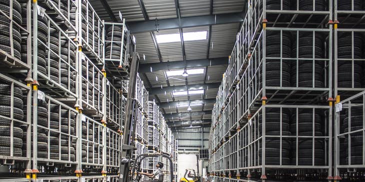 A Freight Handler using a forklift in a warehouse handling and stacking up materials collected.