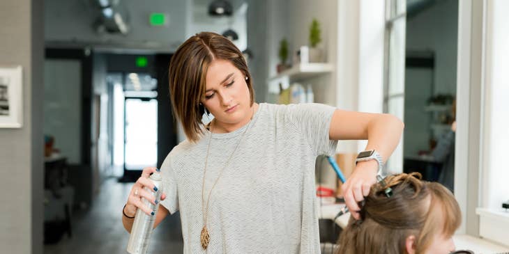 Hair Stylist spraying hairspray on client's hair.