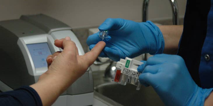 Healthcare Assistant taking blood glucose levels of the patient.