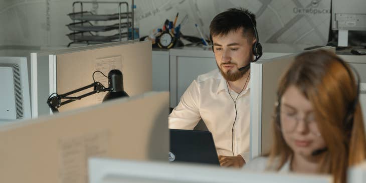 Help Desk Specialist talking to a client over the phone while sitting at his workstation