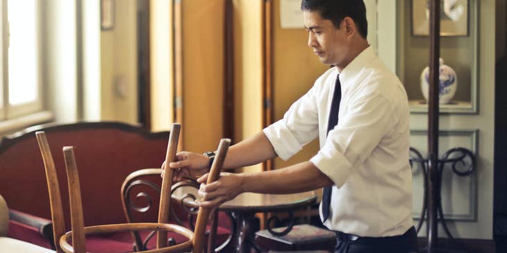A restaurant manager stacking chairs.