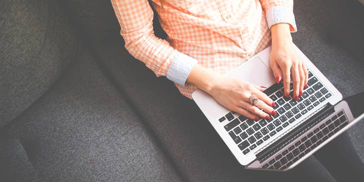 Data entry typist working on a laptop and sitting on a couch at home