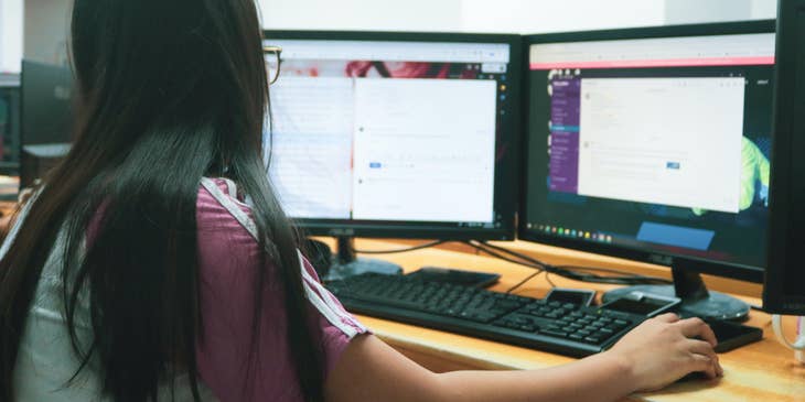 An administrative assistant with black hair sitting at a computer and working.