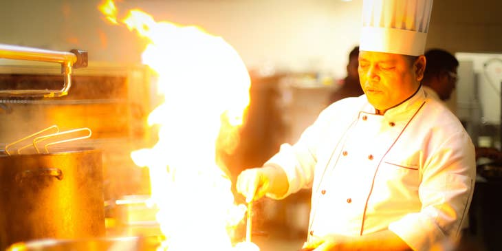 chef flambéing food in kitchen