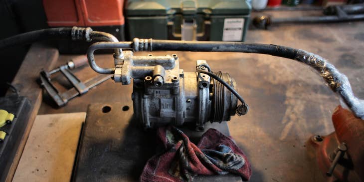 HVAC Service Technician repairing an airconditioner compressor in a workbench