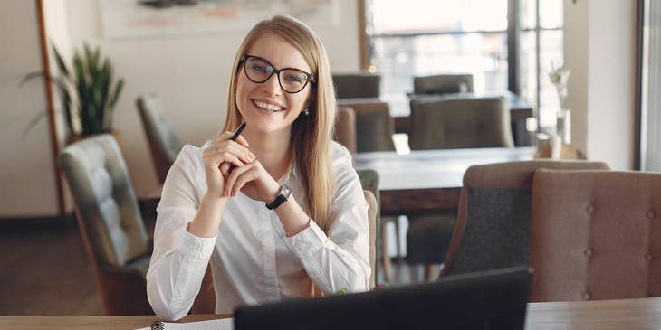 female Investment Banker wearing glasses while sitting in front of her open laptop and notebook