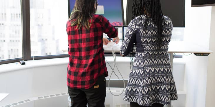 IT Administrator setting up a hardware component on a workstation while her colleague looks on