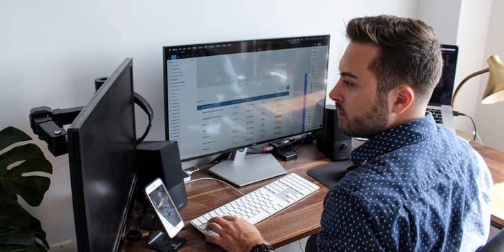 IT Auditor sitting at his workstation and reviewing the overall information system reports