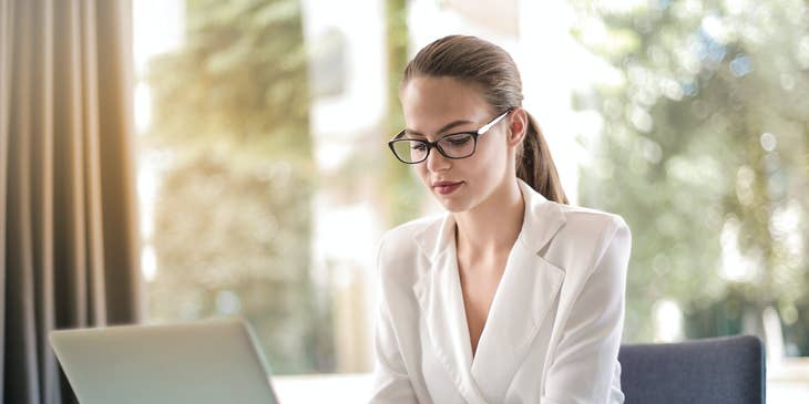 female IT director wearing looking at her laptop while sitting inside her office.